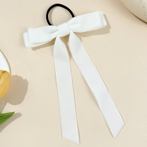Detail eines eleganten weißen Satin-Haargummis mit langen Bändern auf hellem Grund