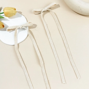 Dettaglio di fermagli per capelli a fiocco crema con nastri lunghi in tessuto