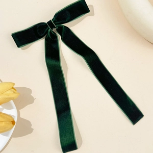 Detail view of the deep green velvet texture on an elegant long bow hair clip