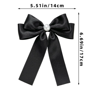 Détail d'une élégante pince à cheveux nœud en satin noir avec une perle blanche centrale