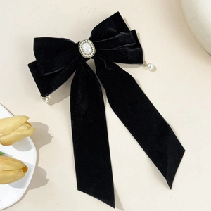 Detailed close-up of a velvet bow hair clip with pearl center and dangling pearl charms