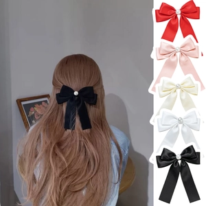 Détail de nœuds à cheveux en satin avec perles en rouge, rose, beige, blanc et noir