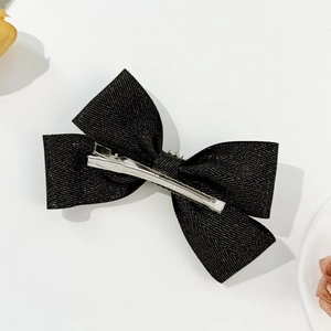 Detail of elegant black tweed bow hair clip with gold metallic threads and silver duckbill clip