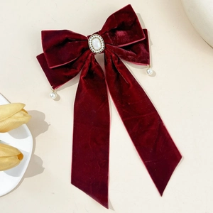 Detail of red velvet bow hair clip with vintage pearl rhinestone and long flowing ribbons