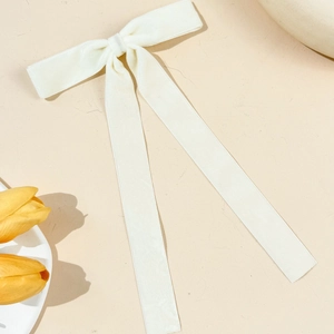 Close-up of a creamy white velvet bow hair clip with elegant long flowing ribbons