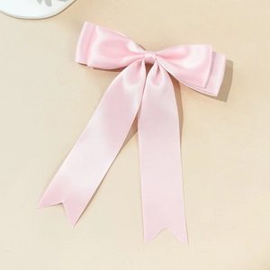Détail d'un nœud papillon en satin rose pâle avec de longs rubans et une texture soyeuse