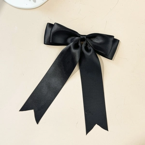 Détail d'un élégant nœud à cheveux en satin noir avec de longs rubans et texture soie