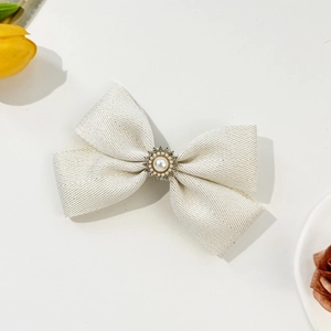 Detail view of cream white herringbone bow hair clip with pearl and rhinestone accent