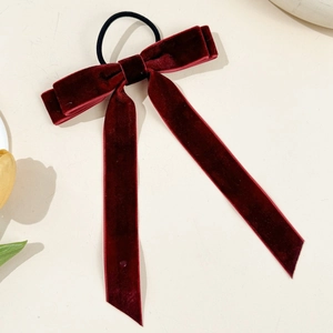 Detailaufnahme des weinroten Samt-Haargummis mit langen Bändern auf beigem Grund