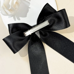 Détail d'une grande pince à cheveux en satin noir avec double nœud et clip en métal argenté