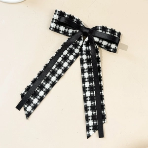 Detail of elegant black and white houndstooth tweed bow hair clip with long satin ribbons