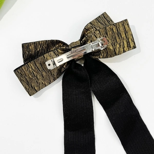Detail of gold pleated fabric and black textile bow with a silver Paris spring metal clip
