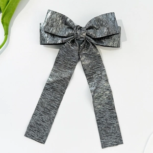 Detail of silver metallic pleated bow hair clip with long ribbons on white background