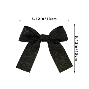 Detail view of black bow hair clip with gold glitter texture measuring 13cm in length