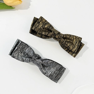 Detailed view of gold and silver metallic crinkle texture bow hair clips on white background