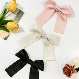 Elegant bow hair clips in pink, cream, and glitter black with herringbone fabric texture