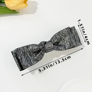 Detail view of the silver metallic bow hair clip with size measurements 13.5cm by 4cm