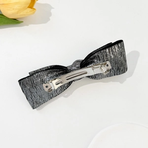 Detailed back view of a silver metallic bow hair clip with textured wavy fabric and spring clip