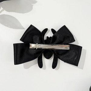 Close-up of black spider bow hair clip showing durable silver metal duckbill clip back