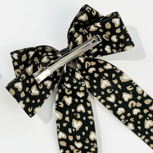 Leopard print bow hair clip with heart patterns and a sturdy silver metal alligator clip