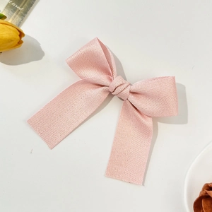 Close-up of pink herringbone texture bow hair clip with long tails on white background