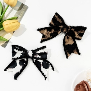 Set of two leopard and cow print bow hair clips with soft fabric texture in retro style