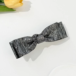 Detailed close-up of metallic silver bow hair clip with vintage crinkle texture finish
