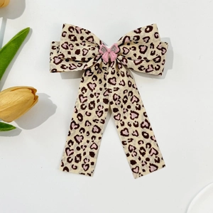 Detailed macro of leopard print bow hair clip with pink crystal butterfly centerpiece