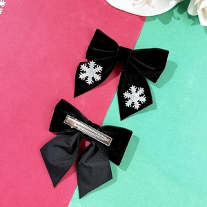 Dettaglio di fermagli per capelli natalizi in velluto nero con fiocchi di neve e clip a coccodrillo