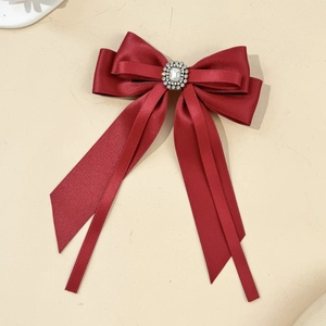 Macro detail of wine red satin bow hair clip with vintage rectangular rhinestone center