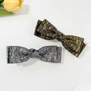 Metallic crinkled bow hair clips in gold and silver colors with textured fabric finish