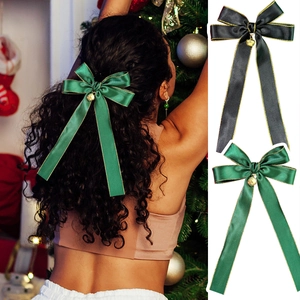 Christmas bow hair clip with gold edges and bell detail shown in a festive holiday setting