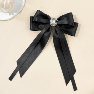 Detail of black satin bow hair clip with central sparkling faux diamond cluster flower