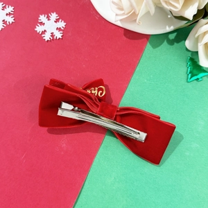 Detalle del lazo de Navidad de terciopelo rojo con letras doradas y pinza de cocodrilo metálica