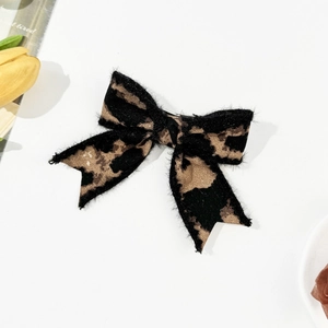 Close-up of leopard print bow hair clip featuring soft plush faux fur texture and fabric detail