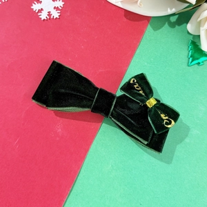 Detalle de pinza para pelo con lazo de terciopelo verde oscuro y bordado dorado navideño