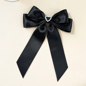 Dettaglio del fiocco per capelli in raso nero con strass a cuore scintillante