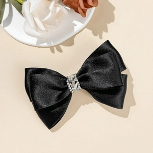 Gros plan d'une barrette à nœud en satin noir avec détails en strass de luxe