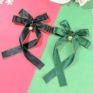 Close-up of satin bow hair clips with gold stitched edges and festive bells
