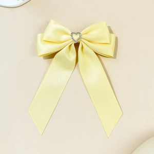 Dettaglio di un fermaglio per capelli in raso giallo pallido con strass a cuore al centro