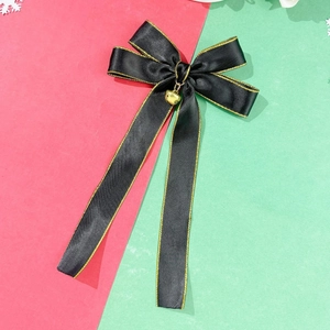 Close-up of black satin bow hair clip with gold edge and heart pendant on festive background