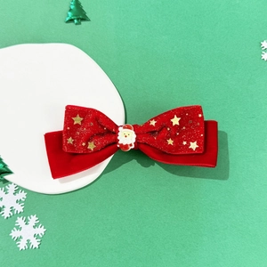 Detailansicht der roten Samt-Haarschleife mit goldenen Sternen und Weihnachtsmann