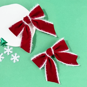 Makroaufnahme von roten Weihnachtsschleifen aus Samt mit weißem Pelzbesatz auf Mintgrün