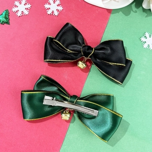 Detail of Christmas bow hair clips with gold bells and metal duckbill clip on festive background