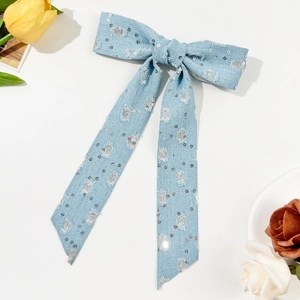 Dettaglio del fermaglio a fiocco in denim blu con paillettes e bordi sfrangiati
