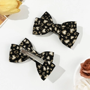Detail view of leopard print bow hair clips with silver metal duckbill clips on white background