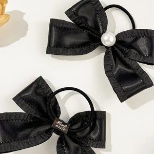 Detail of black ribbon hair ties with white pearl accent and handmade label tag