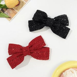 Detail of sequined tweed bow hair clips in red and black with elegant texture
