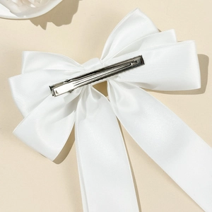 Detail view of the silver alligator clip on the back of the white satin bow hair accessory