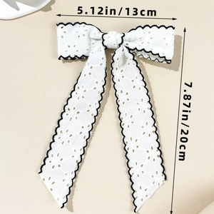 Detail view showing white lace bow hair clip with black stitching and size measurements